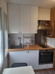una cocina con armarios blancos y fregadero en Studio 5min aéroport d'Orly 2 lits en Athis-Mons