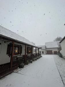 a snow covered yard with a house and a building at Casa Matteo - Rustic & cosy getaway in Zărnești in Zărneşti