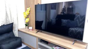 a large flat screen tv sitting on a wooden stand at Portal das Palmeiras 2 in Ubatuba