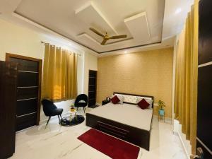 a bedroom with a bed and chairs in a room at ATULYAM HARSHADA STAYS LUCKNOW in Goshainganj