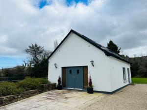 a small white building with a green door at Winton Grove – for outdoor and tennis enthusiasts in Kilmacanoge