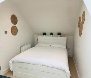 Una cama blanca con dos plantas encima. en Winton Grove – for outdoor and tennis enthusiasts, en Kilmacanoge