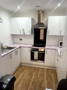 cocina con armarios blancos y fogones en Cozie 1 BR apartment en Mánchester