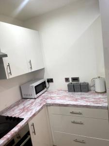 eine Küche mit einer Arbeitsplatte und einer Mikrowelle in der Unterkunft Cozie 1 BR apartment in Manchester