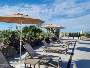 een rij stoelen en parasols op een patio bij Costa Adeje Garden Aparthotel in Adeje