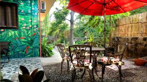 un patio con mesa, sillas y sombrilla roja en EspIliNorte, Stay and Play, en San Juan