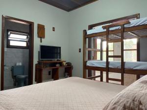 een slaapkamer met 2 stapelbedden en een televisie bij LARA'S HOUSE in São Sebastião