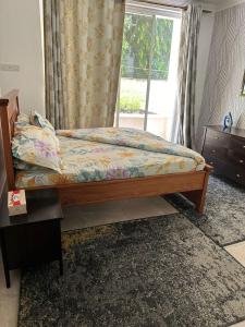a bedroom with a bed with a window and a table at Masaki - 2 Bedroom Apartment in Dar es Salaam