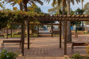 einen Pavillon mit Bänken und Palmen in einem Park in der Unterkunft C55 Cosy studio close to the beach in Málaga