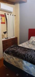 um quarto com uma cama e uma cómoda com um candeeiro em Alojamiento El Jilguero em Puerto Iguazú