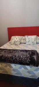 uma cama com uma cabeceira vermelha e um cobertor em Alojamiento El Jilguero em Puerto Iguazú
