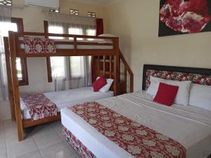 a bedroom with two bunk beds with red pillows at Rosella Cottage - Homestay - Kitchen Yogyakarta in Yogyakarta