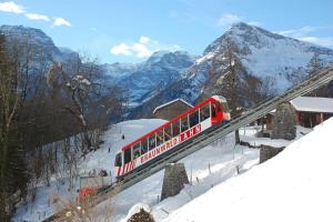 a red and white train on a bridge in the mountains at Zimmer für Bergfreunde - Das gemütliche Haus des Grossvaters - Bergheimat - Ganz einfach - ganz unkompliziert - ganz relaxd in Linthal