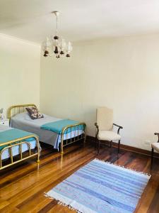 1 dormitorio con 2 camas, silla y alfombra en Casa Alparaiso, en Valparaíso