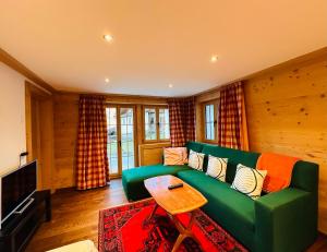 a living room with a green couch and a table at One Bedroom with mountain and garden view ground floor of Chalet Solaria in Zweisimmen