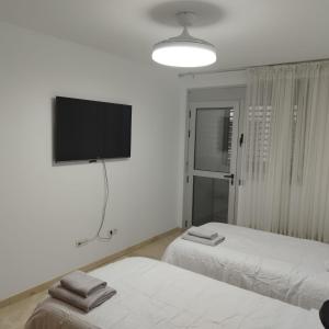 Dieses weiße Zimmer verfügt über 2 Betten und einen Flachbild-TV. in der Unterkunft MAND CANTERAS in Las Palmas de Gran Canaria