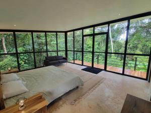 sypialnia z łóżkiem i dużymi szklanymi oknami w obiekcie Cascada Elysiana w mieście Platanillo