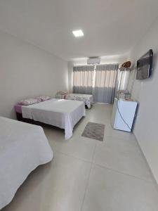 a white room with two beds and a tv at Pousada Castelo do Rei in Penha