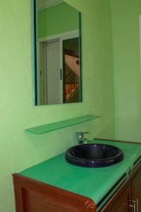 een groene badkamer met een wastafel en een spiegel bij Très belle maison in Sidi Ifni