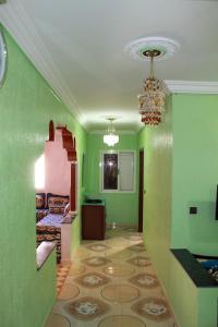 een groene kamer met een bed en een kroonluchter bij Très belle maison in Sidi Ifni