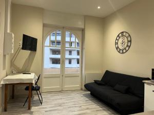 a living room with a couch and a clock on the wall at ALTA in Bourg-lès-Valence