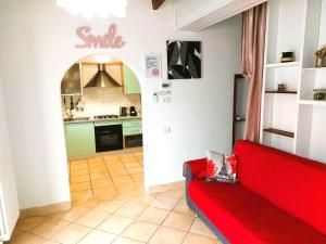 a living room with a red couch and a kitchen at Confortevole Appartamento Il Sorriso piano terra ingresso e parcheggio indipendente per una tranquilla privacy in Lugo