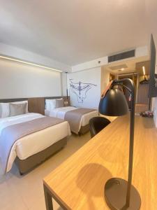 um quarto de hotel com duas camas e uma secretária com um candeeiro em Tryp by Wyndham Brasília Nações em Brasília