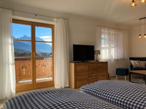 a bedroom with a bed and a television and a window at Ferienwohnungen LARA Wohnung 2 in Wallgau