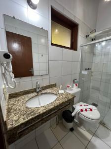 a bathroom with a sink and a toilet and a mirror at Pousada Villa N'kara in Itacaré
