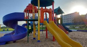 um parque infantil com escorrega na areia em Eleganza Suites em Kilifi