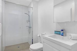 a white bathroom with a shower and a toilet at Entire home with parking in Parramatta in Sydney