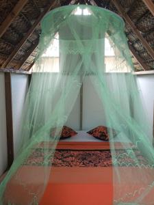 a bed with a net on top of it at Moanarani Camping in Avatoru