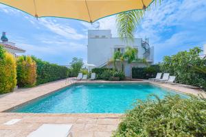 a swimming pool in front of a house with an umbrella at Lucrezia relax in Nardò +22 photos