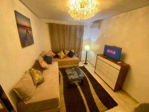 uma sala de estar com um sofá e uma televisão em Chic & Cosy au coeur d’hivernage em Marrakech