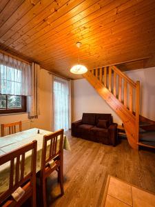 een woonkamer met een houten plafond en een trap bij Apartmany Kolb Ramzová in Ostružná