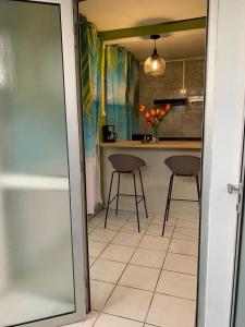 uma cozinha com um balcão e dois bancos em Logement avec parking à proximité de l’aéroport em Les Abymes