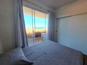 ein Schlafzimmer mit einem Bett und einem großen Fenster in der Unterkunft Lindo 2 Qts Vaga Búzios vista deslumbrante do Mar in Búzios