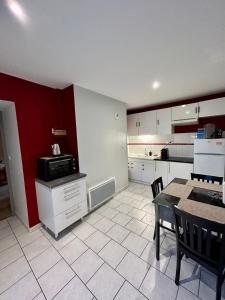 a kitchen with white cabinets and a table with a microwave at Charmant studio de 50 m2 in Chaumont
