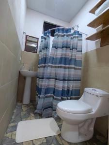 a bathroom with a toilet and a shower curtain at Papaturro House in La Cruz