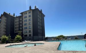 a swimming pool in front of a building at Departamento Costanera Villarrica in Villarrica