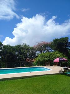 ein Pool mit Sonnenschirm neben einem Hof in der Unterkunft casa do morro linda vista para ate 08 pessoas in Imbituba