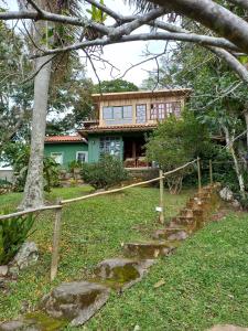 ein Haus mit einem Baum und einer Treppe davor in der Unterkunft casa do morro linda vista para ate 08 pessoas in Imbituba