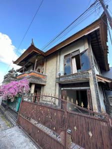 stary dom z płotem przed nim w obiekcie Rodin Bali Hostel w mieście Seminyak