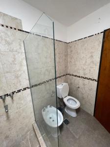 uma casa de banho com um WC e uma cabina de duche em vidro. em Brisas del Sur em Villa Carlos Paz