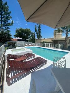uma piscina com duas espreguiçadeiras e um guarda-sol em Brisas del Sur em Villa Carlos Paz