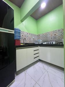 - une cuisine avec des placards blancs et des murs verts dans l'établissement Chalé em Barreirinhas - MA, à Barreirinhas