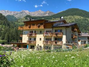 un edificio con balcone e montagne sullo sfondo di Hotel Ortles Dolomiti Walking & Spa a Cogolo