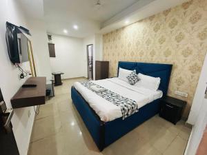 a bedroom with a blue bed and a flat screen tv at Hotel Kelvish by Foxi Group in New Delhi