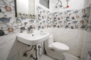 a white bathroom with a sink and a toilet at Hotel Kelvish by Foxi Group in New Delhi