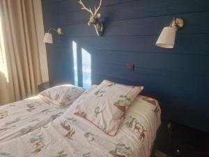 a bed with two pillows and a blue wall at Appartement La Duchère Le Plan-la Giettaz massif des Aravis in La Giettaz